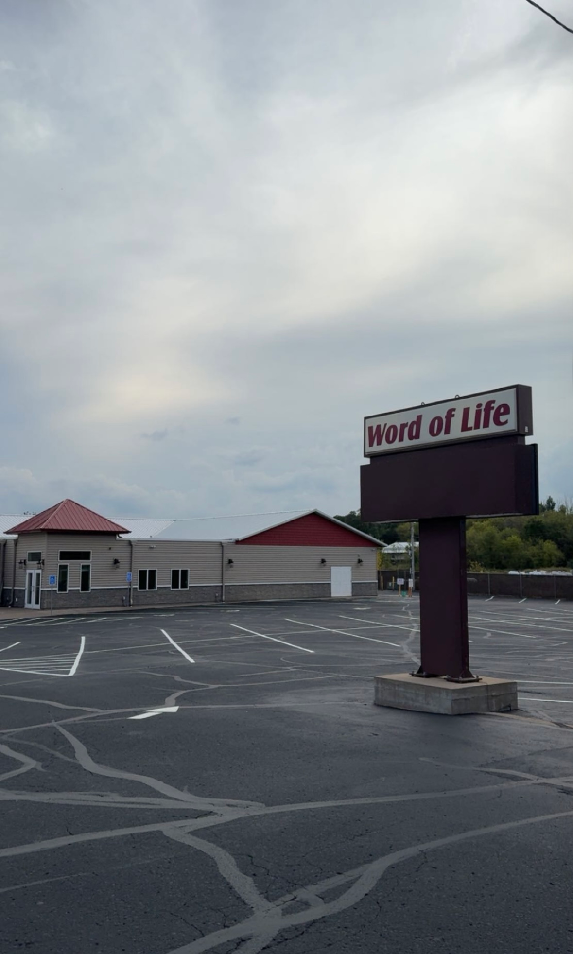 Empty parking lot outside a Word of Life church building under a cloudy sky