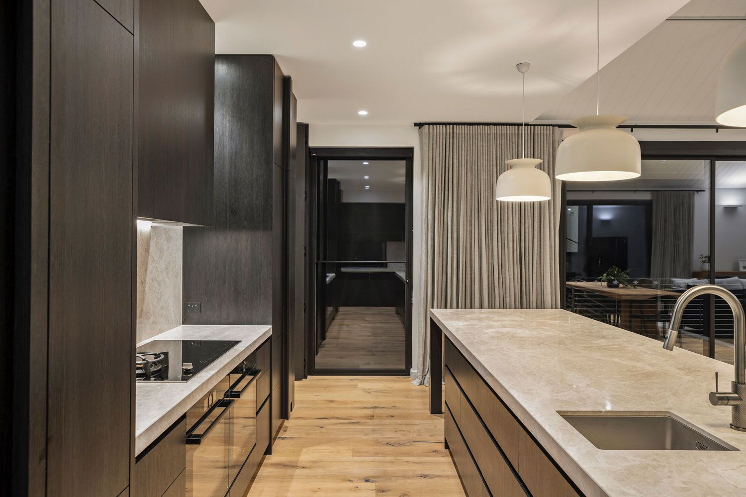 Modern kitchen with dark cabinetry, light countertops, and island.