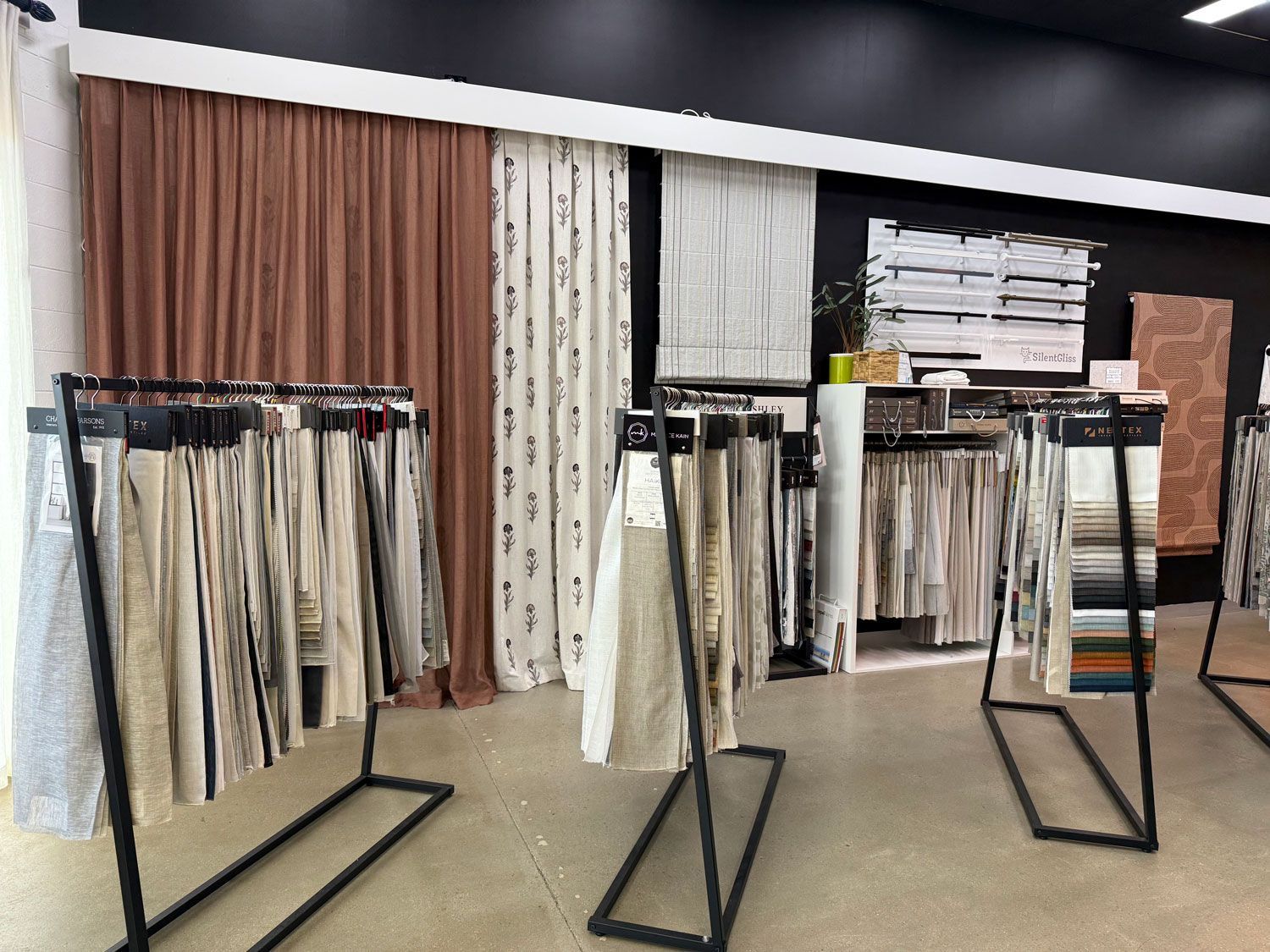 Fabric samples and curtains displayed in a store, showcasing various colors and textures.