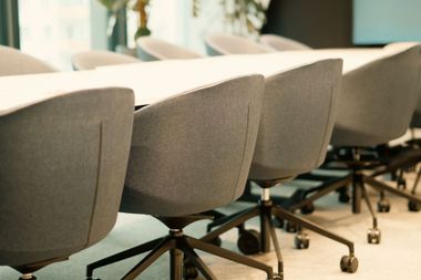 Gray office chairs on wheels lined up in a conference room with a light wood floor