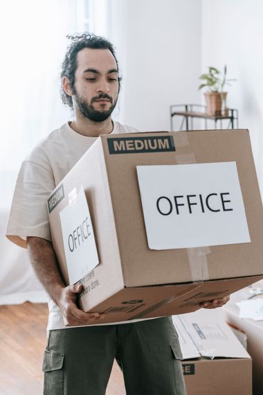 Person carrying cardboard boxes labeled 
