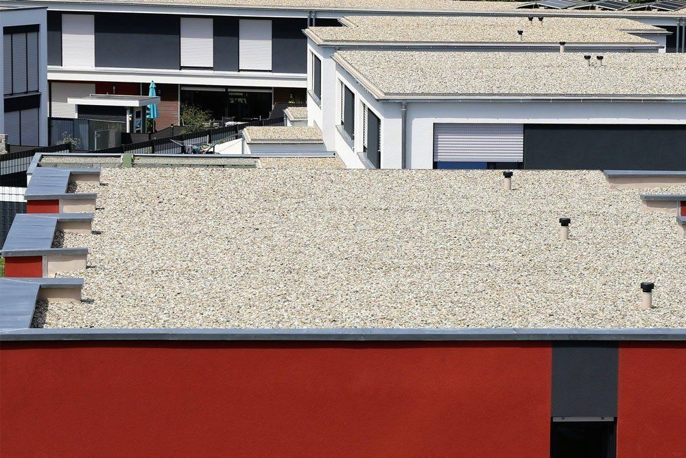 Modern flat rooftops with gravel, skylights, and red-and-gray building facades