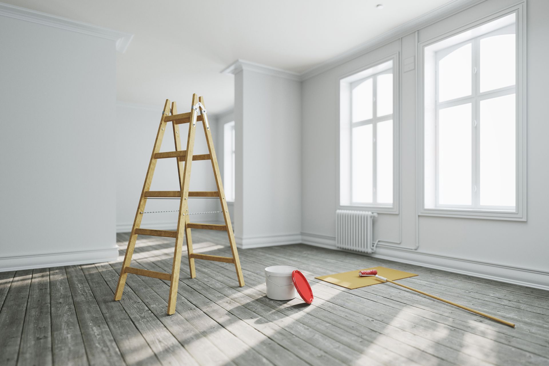 Bright empty room with a wooden ladder, paint tray, and drop cloth, suggesting home renovation