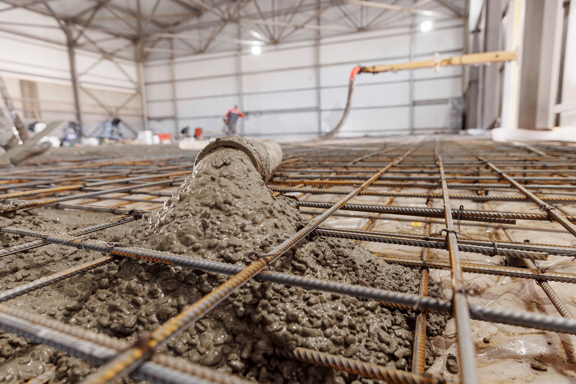 Wet concrete poured over rebar in a large industrial construction site
