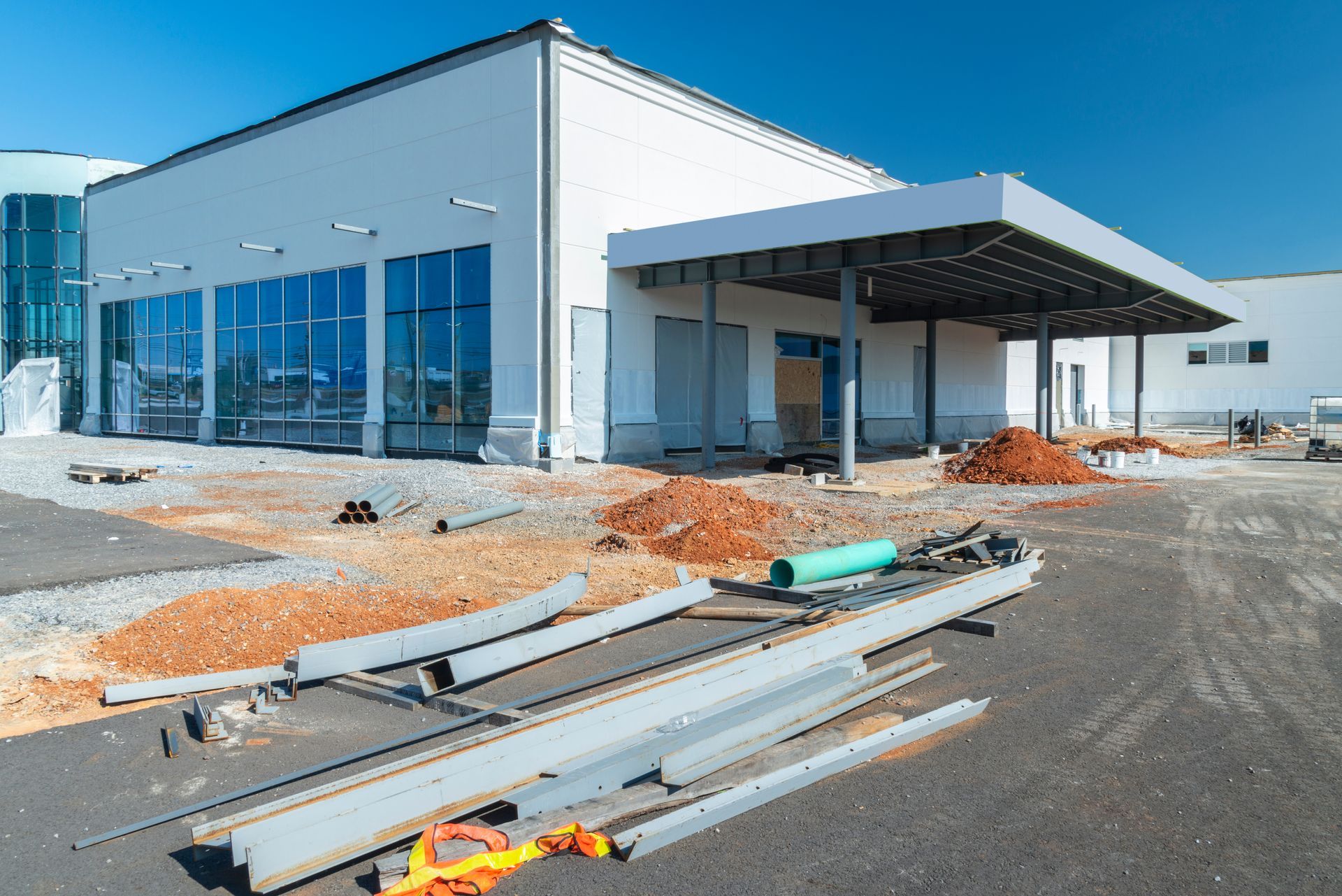 Modern commercial building under construction with glass windows, steel beams, and gravel foreground