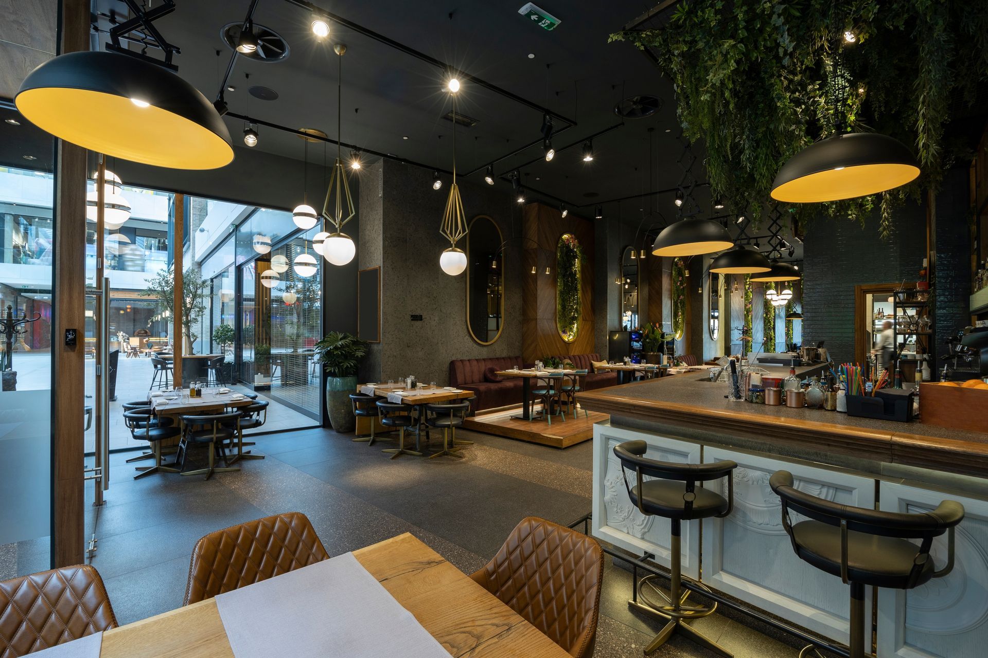 Modern café interior with tables, bar seating, hanging lights, and large windows