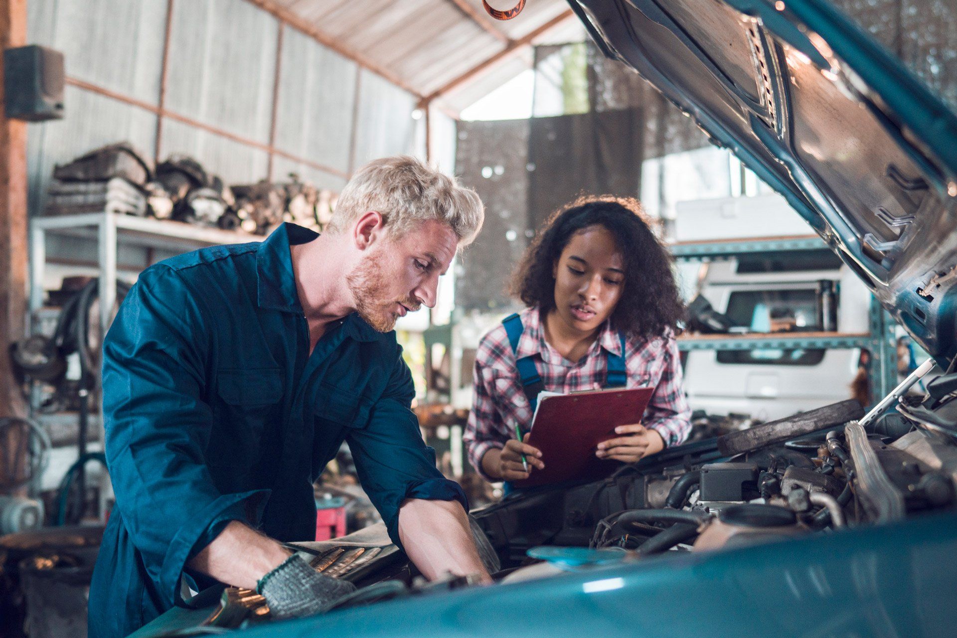 A woman looking in the paper while the man repairing the car | Sydney, NSW | Autocure Mobile Mechanics A woman looking in the paper while the man repairing the car | Sydney, NSW | Autocure Mobile Mechanics