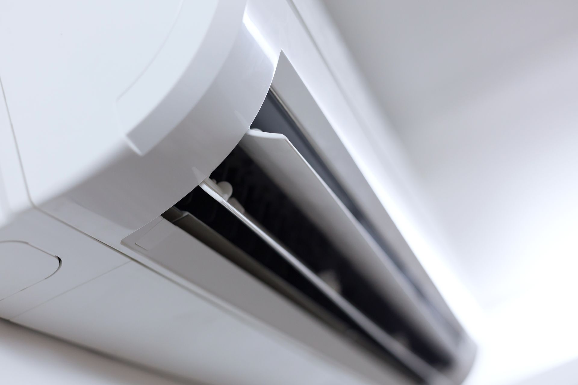 Wall-mounted white air conditioner with open vents, seen from below