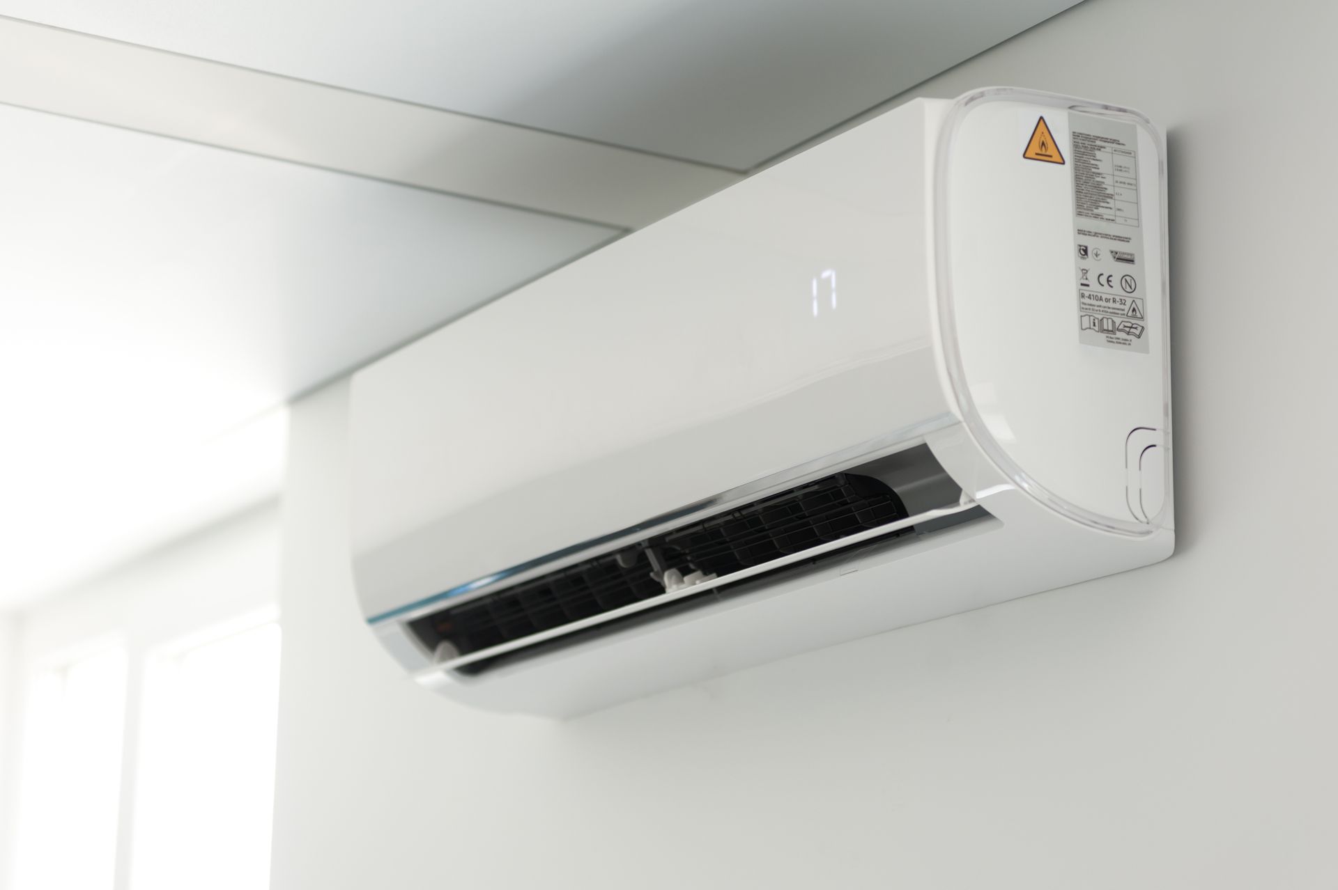 White wall-mounted air conditioner near the ceiling in a bright room