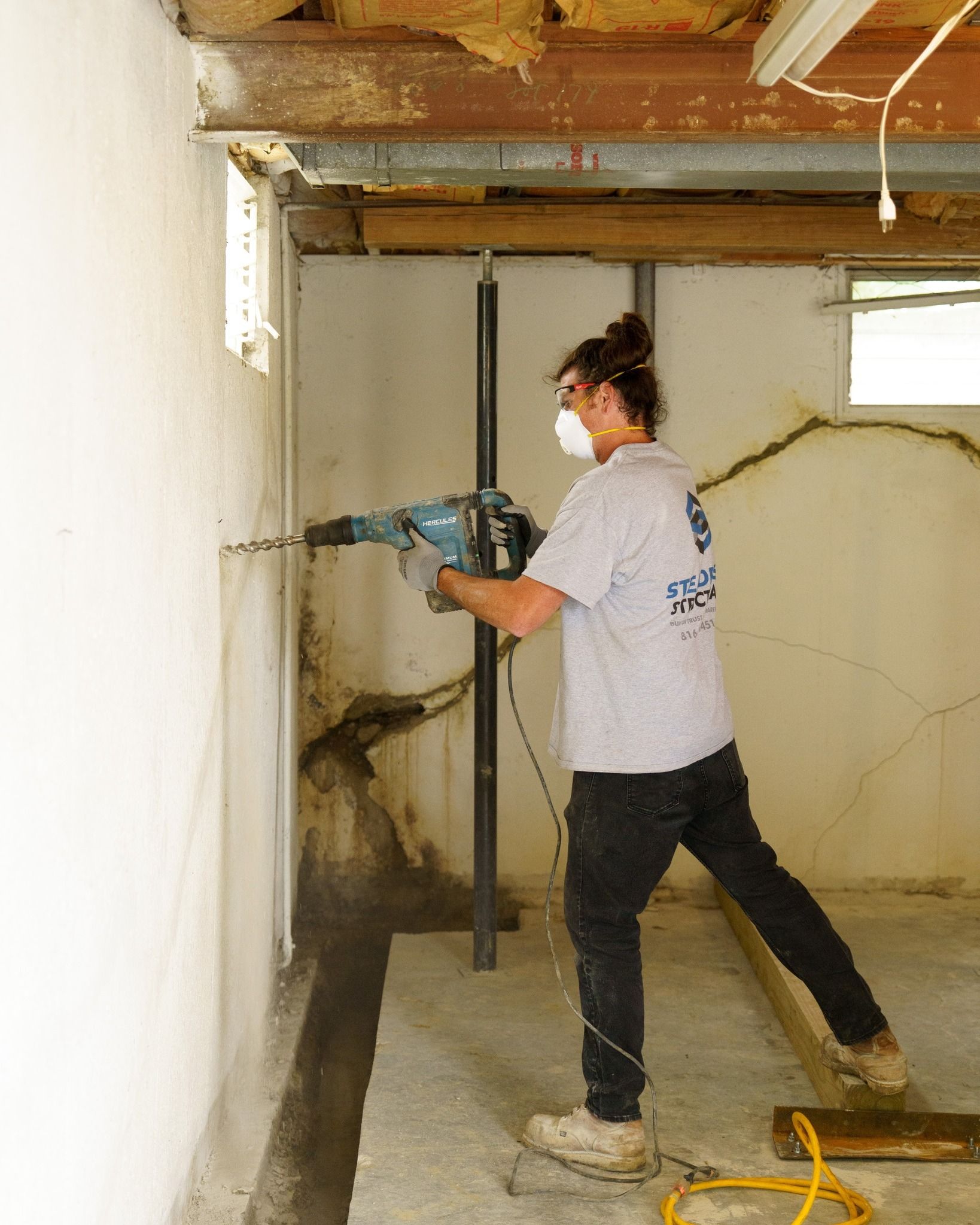 Person using a power drill to break through a wall in an unfinished room