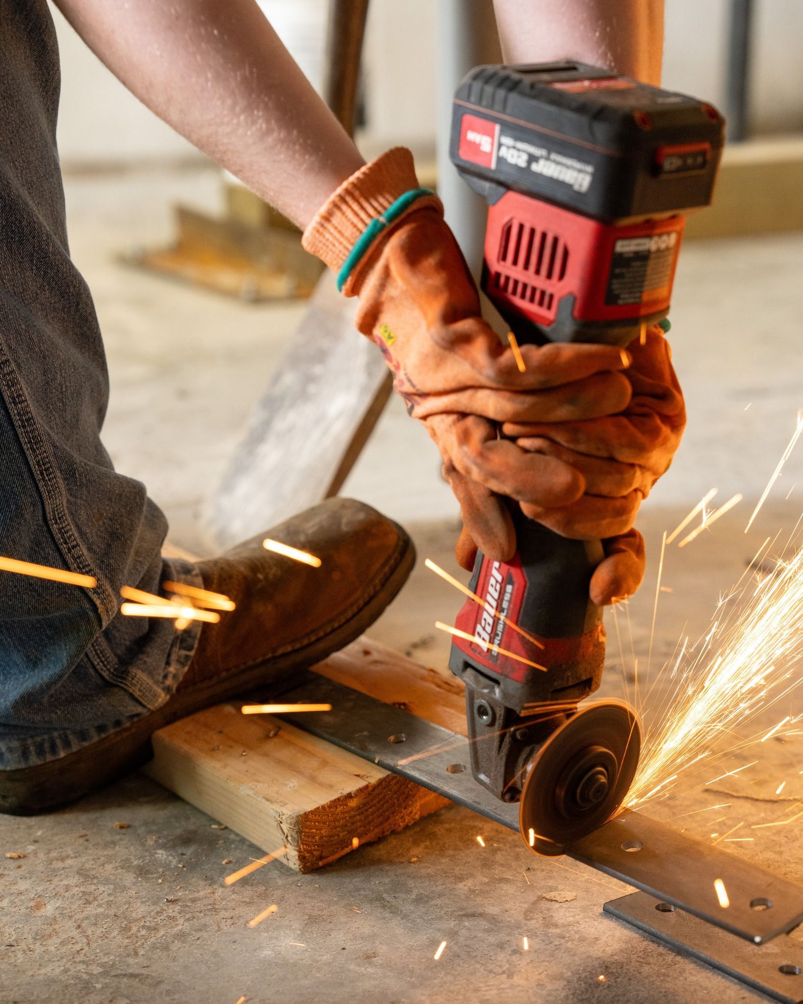 Person using a power grinder on wood, with sparks flying in a workshop.