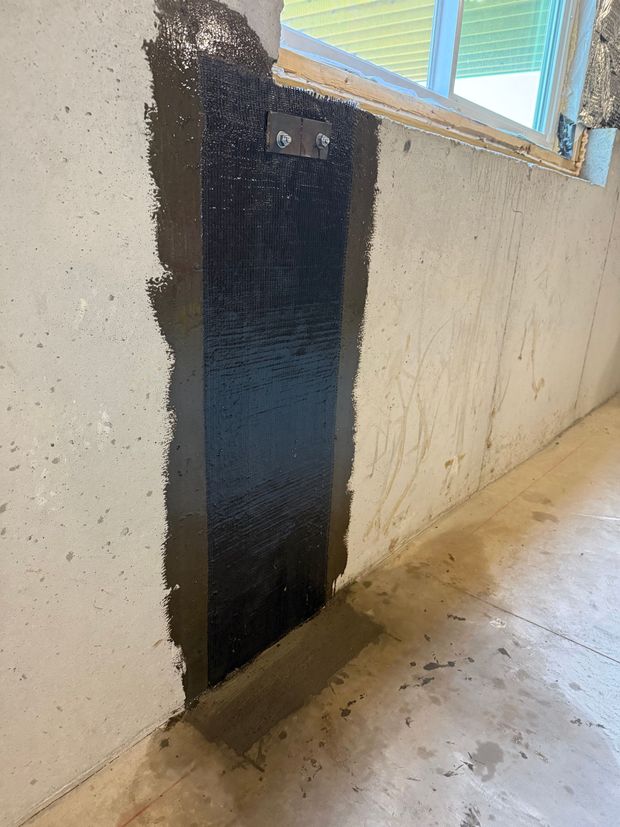 Black painted vertical panel on a white concrete wall in a hallway beneath a window.