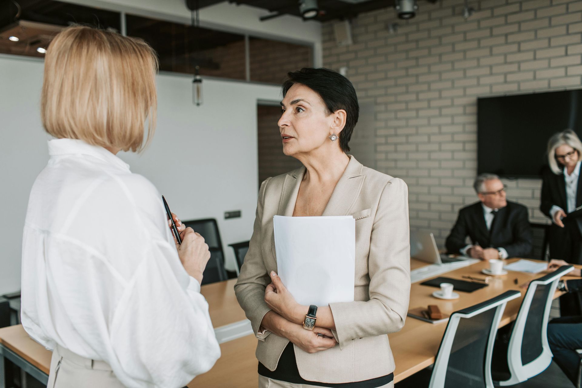 Two women are talking to each other in a conference room.