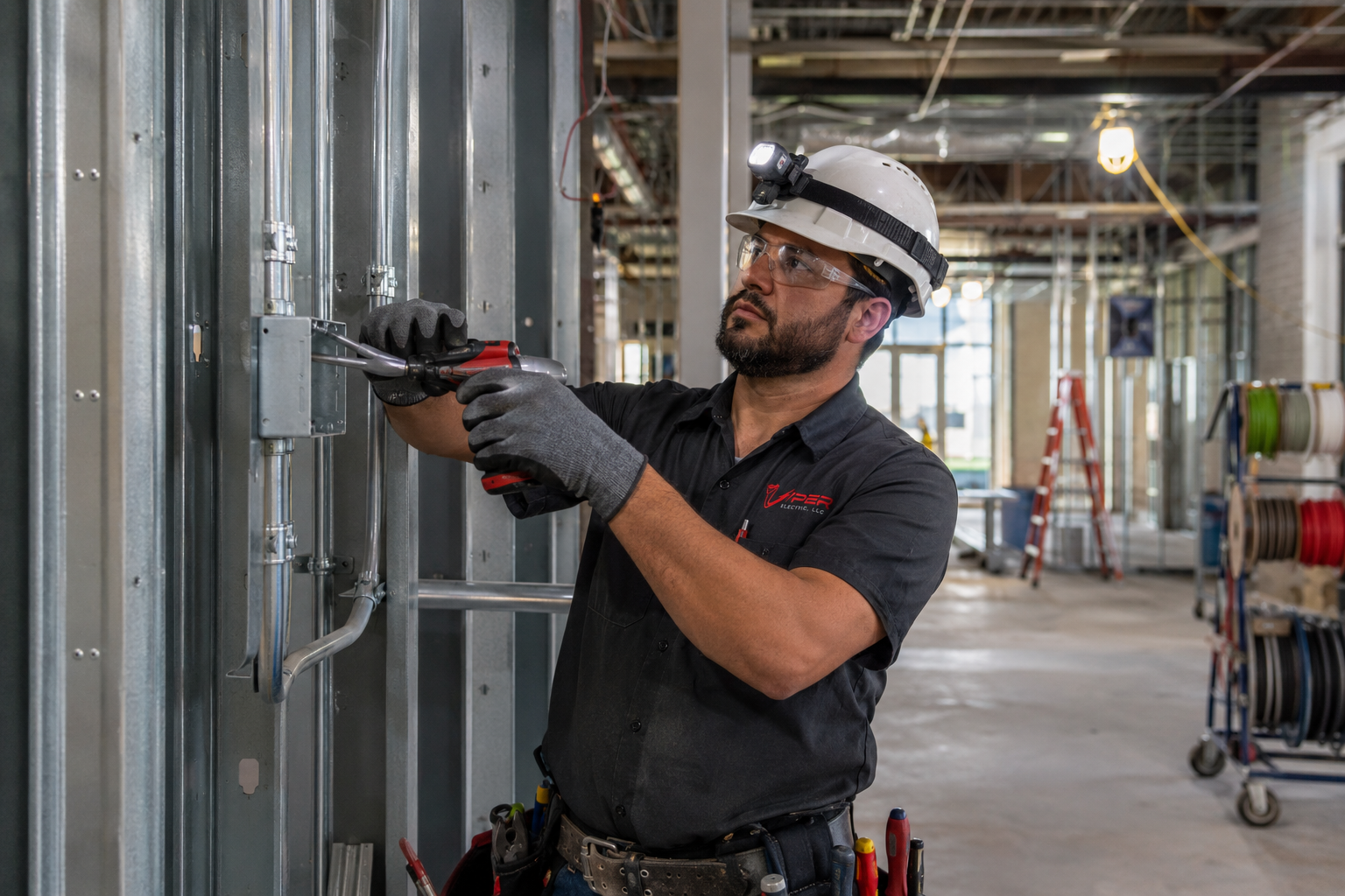 Construction worker wiring an unfinished interior wall in a building under renovation