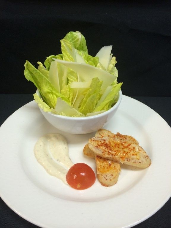 A white plate with a bowl of lettuce and chicken on it