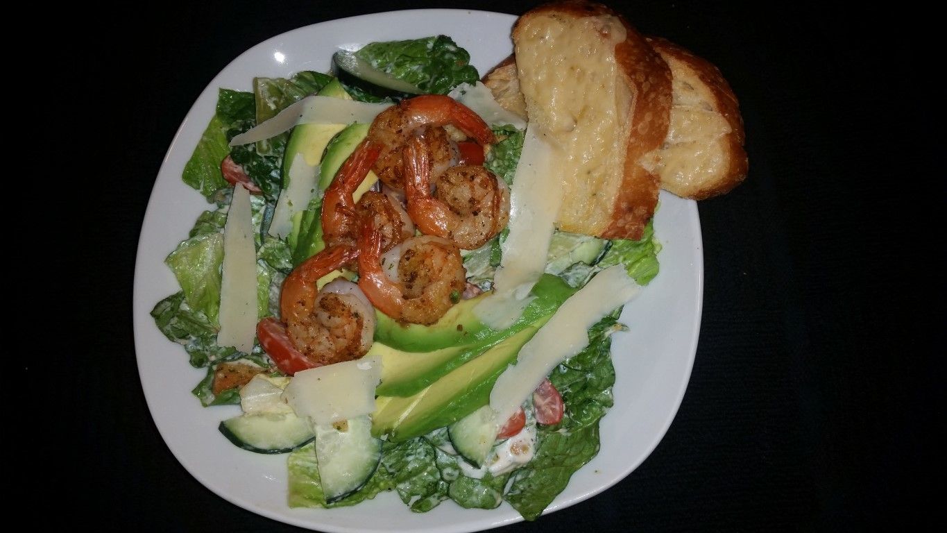 A salad with shrimp and avocado on a white plate