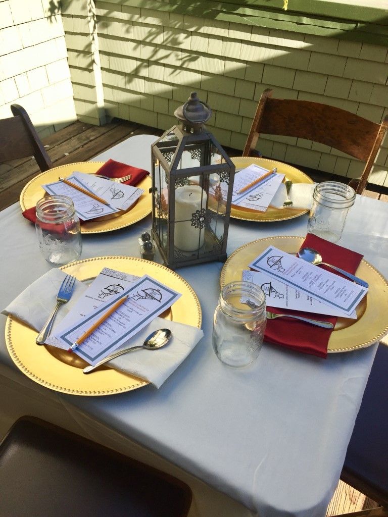 A table with plates , napkins , glasses , and a lantern on it.