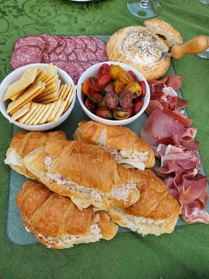 A plate of food with croissants , crackers , and meat on a table.