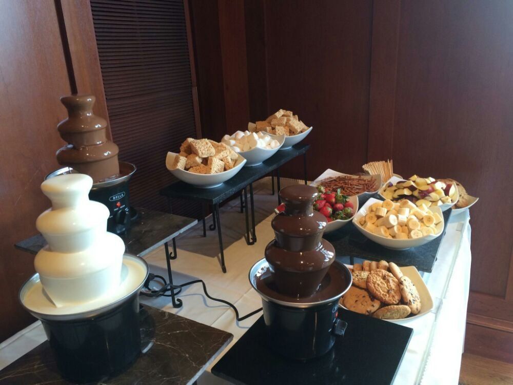 A table with chocolate fountains and a variety of snacks on it