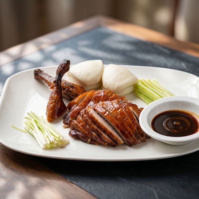 Plated roasted meat with rice cakes, white radish, and dipping sauce on a white plate