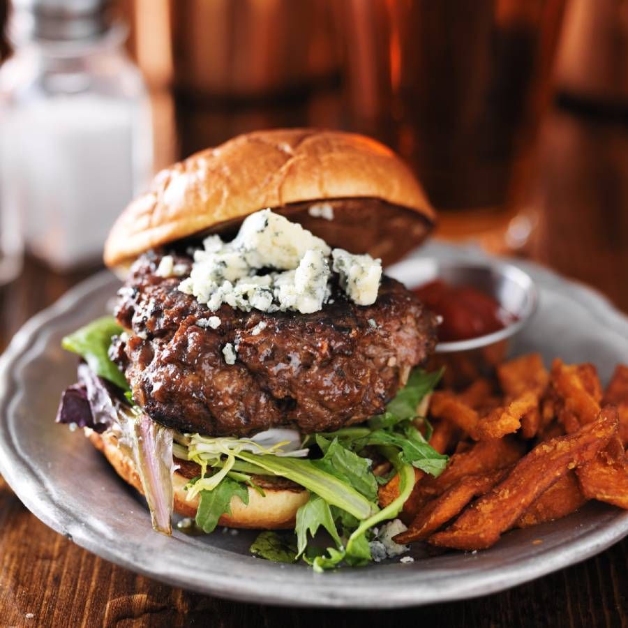 A hamburger with blue cheese and french fries on a plate