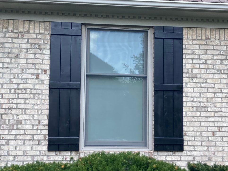 Board and Batten Exterior Shutters Lexington, KY A white brick house with black shutters on the windows.