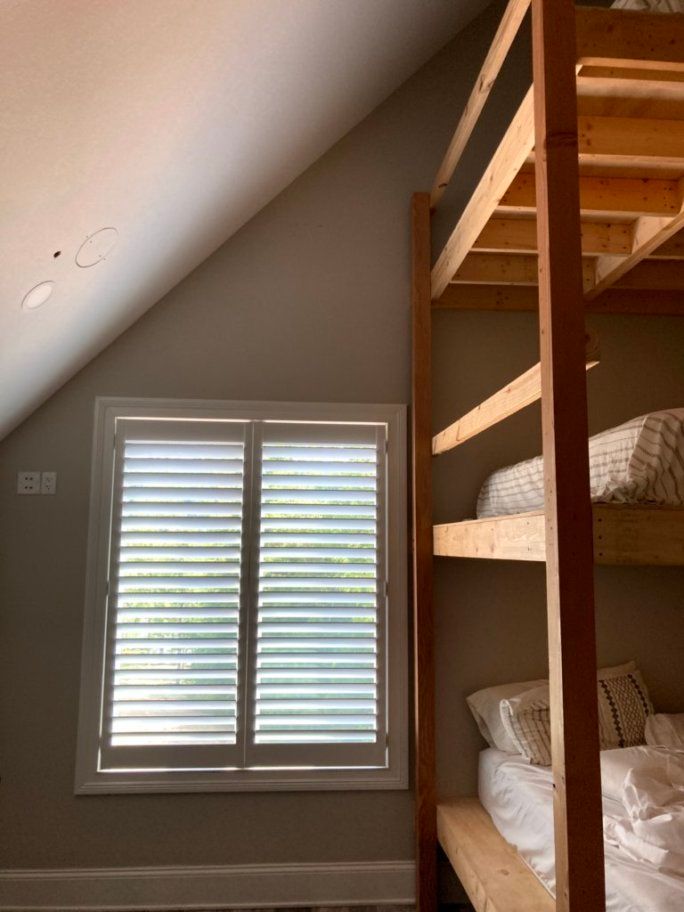 A bedroom with bunk beds and a window with shutters.