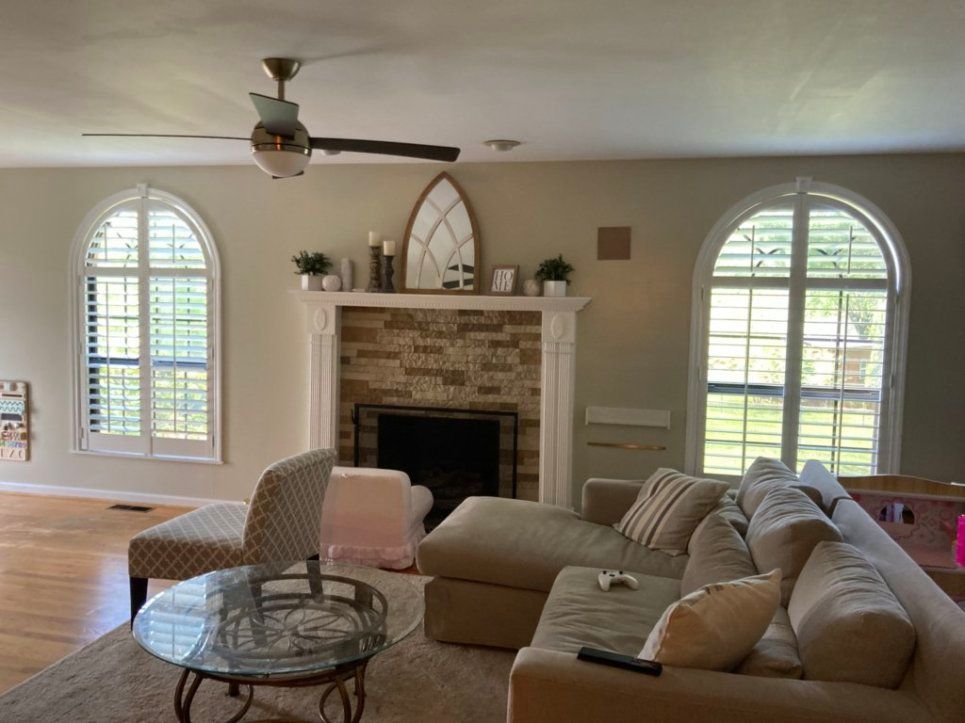 Living room with fireplace, arched windows, and beige sectional sofa.