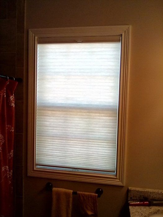 There is a window in the bathroom with blinds on it.