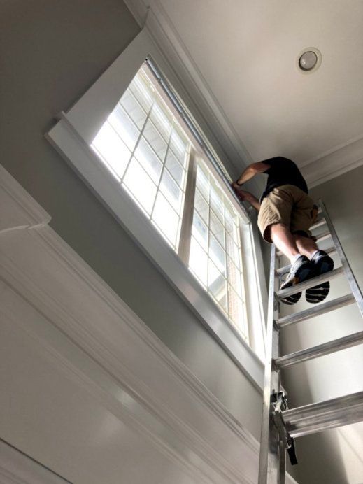 A man on a ladder looking up at a window