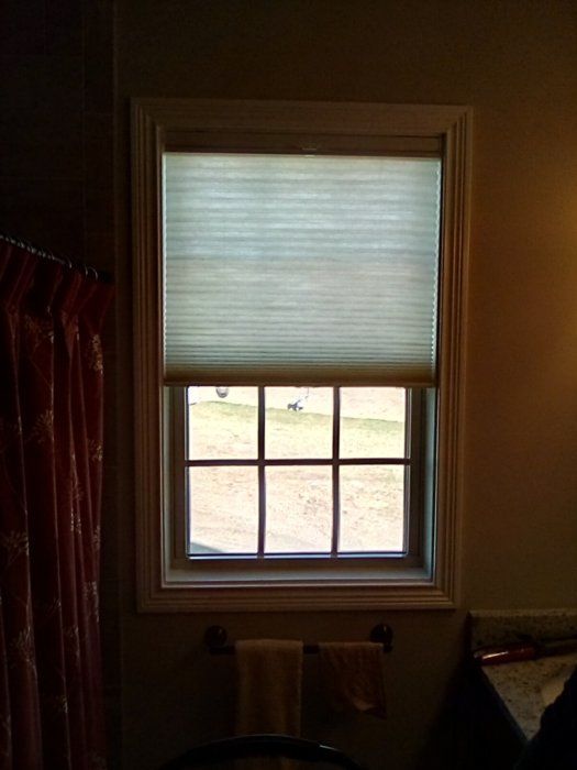 A window with a blind on it in a bathroom.