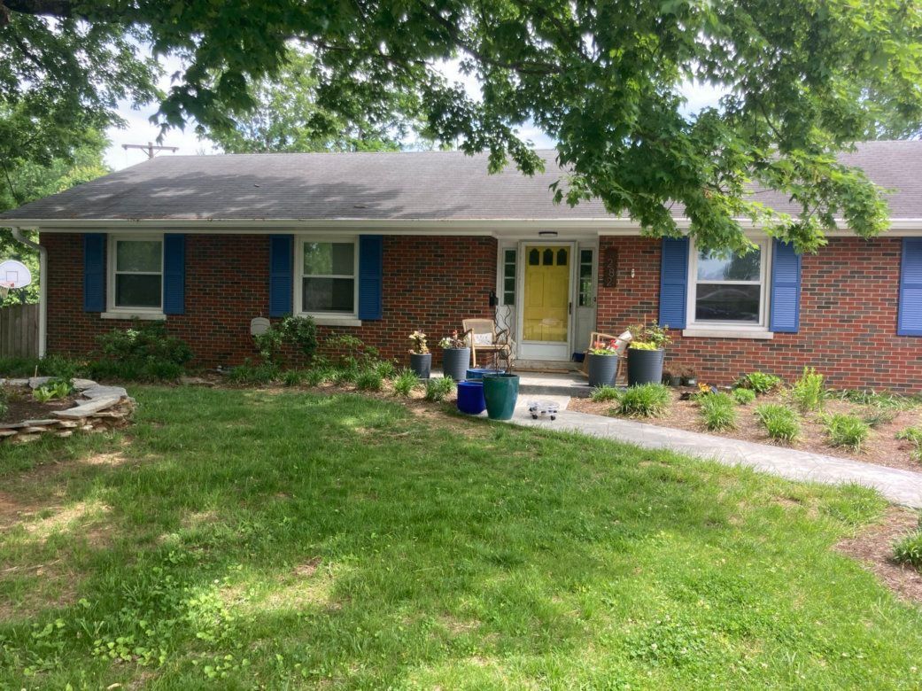 A brick house with blue shutters and a yellow door.