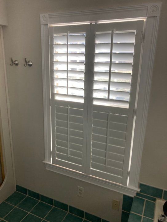 A bathroom with a window with shutters on it