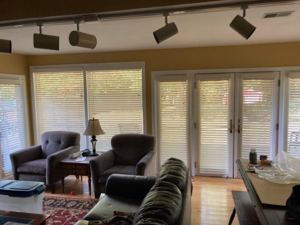 A living room with a couch and chairs and blinds on the windows
