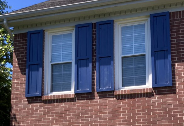Raised Panel Exterior Shutters Lexington, KY A brick house with blue shutters on the windows