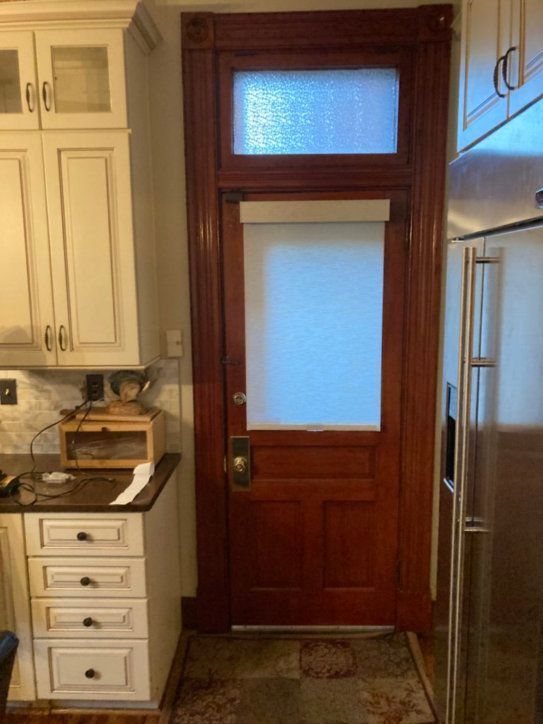 A kitchen with a red door and white cabinets