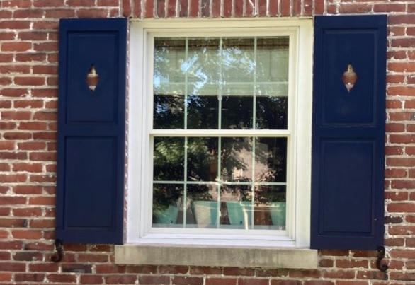 Special Cut Exterior Shutters Lexington, KY A window with blue shutters on a brick wall
