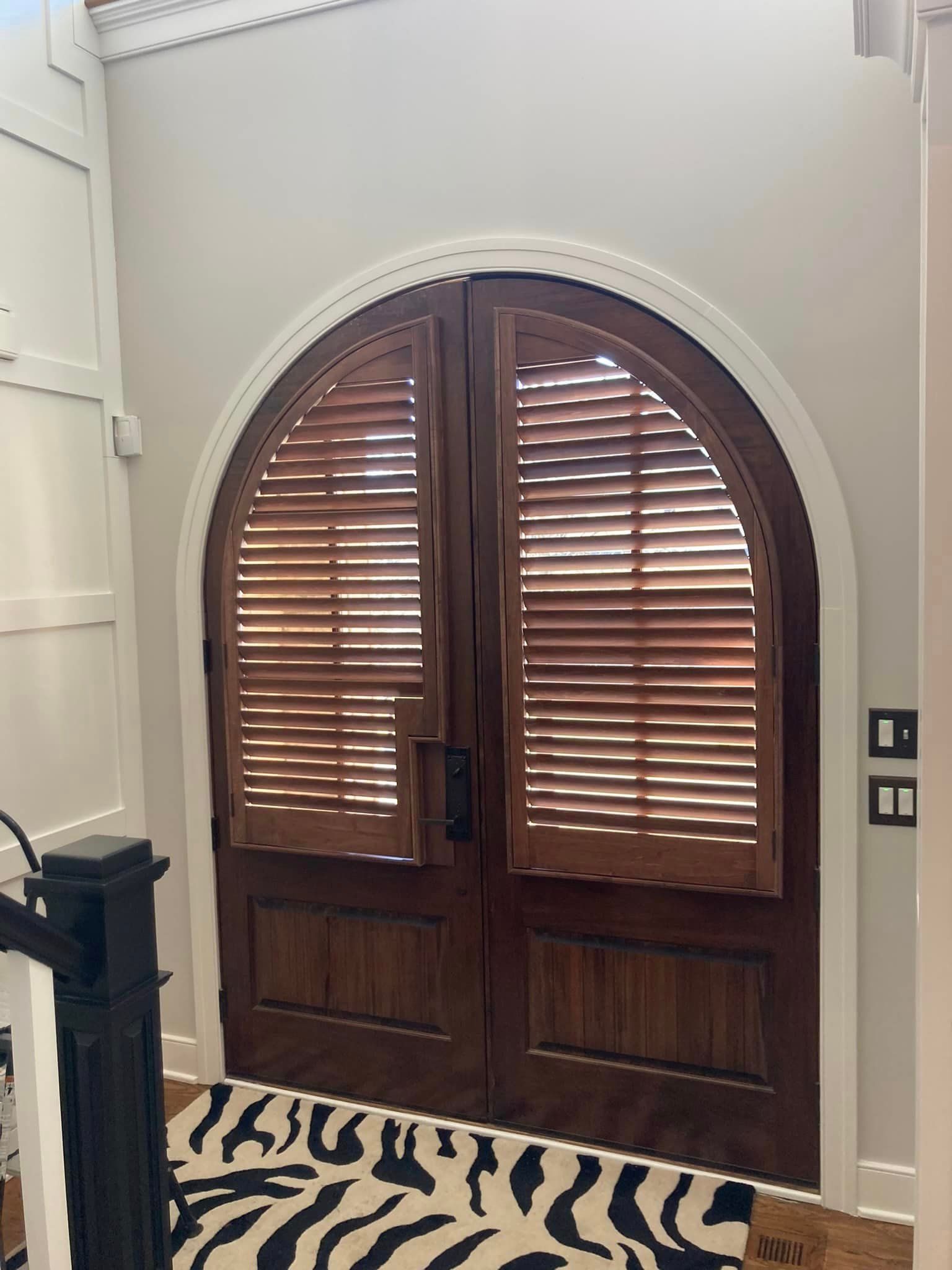 A door with shutters on it and a zebra print rug in front of it.