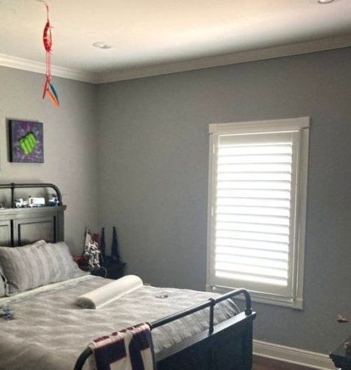 A bedroom with a bed and a window with blinds