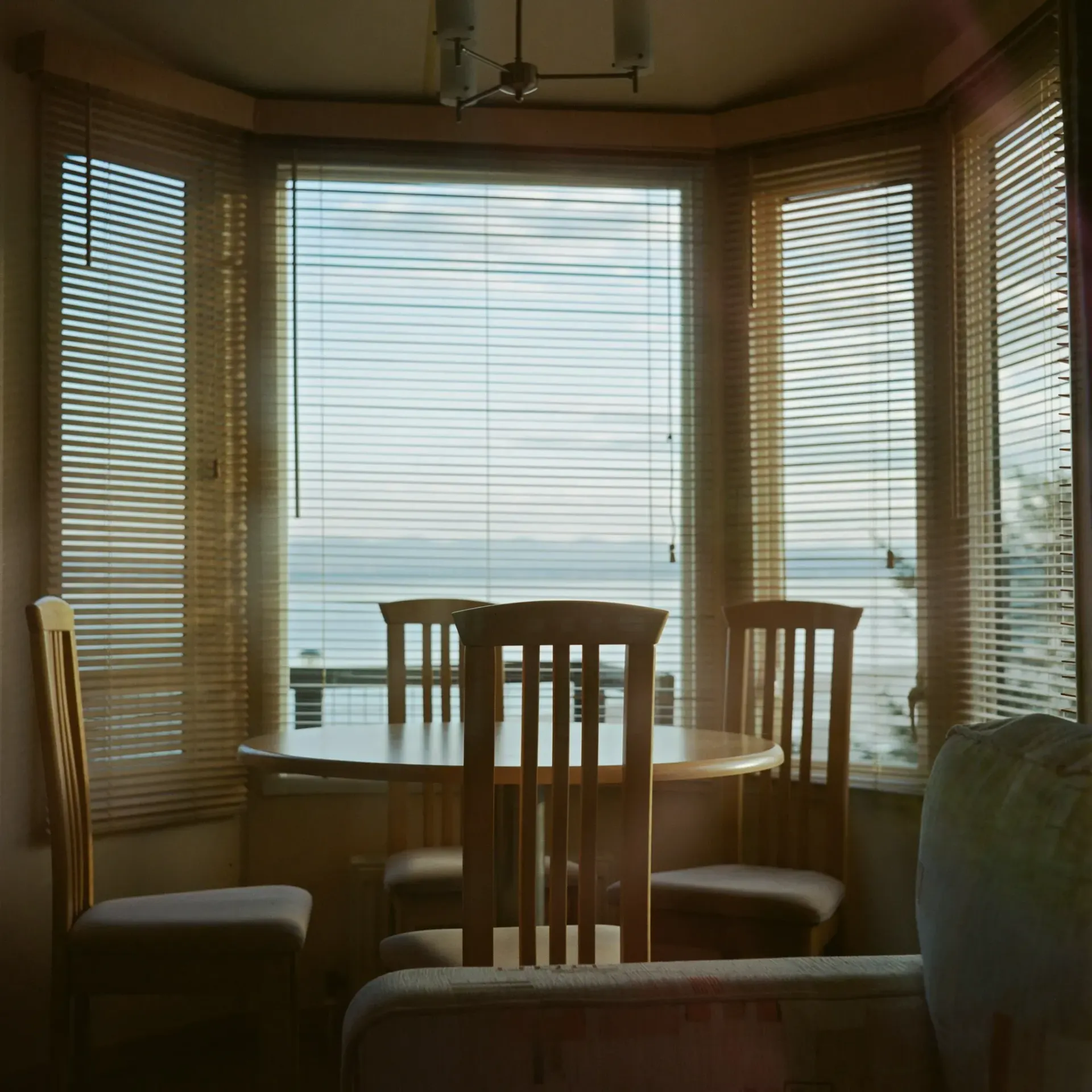 A table and chairs in front of a window with blinds