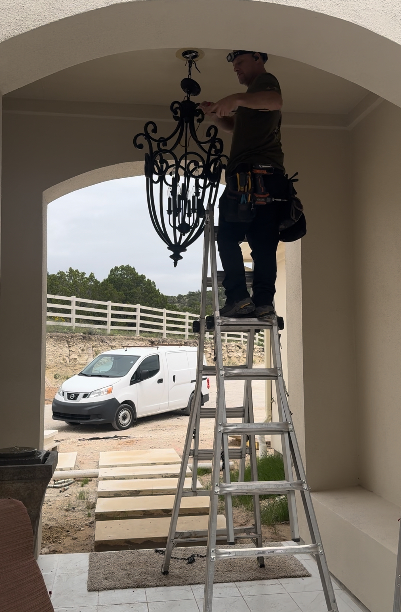 A man standing on a ladder working on a chandelier