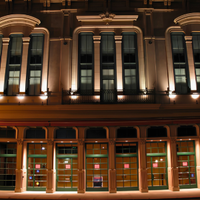 Nighttime view of an ornate historic building facade with warm lights and arched windows