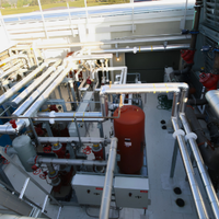 Industrial plant with white pipes, red tank, and metal platforms viewed from above