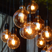 Warm glowing pendant light bulbs hanging in a cluster against a dark background