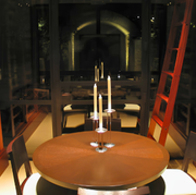 Modern wine cellar with circular wooden table, central candles, and rows of illuminated wine racks