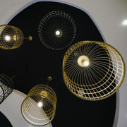 Abstract ceiling lights in gold, white, and black hanging against a black-and-white ceiling cutout.