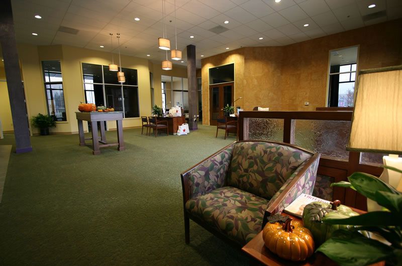 Cozy hotel lobby with green carpet, armchairs, lamps, and warm lighting