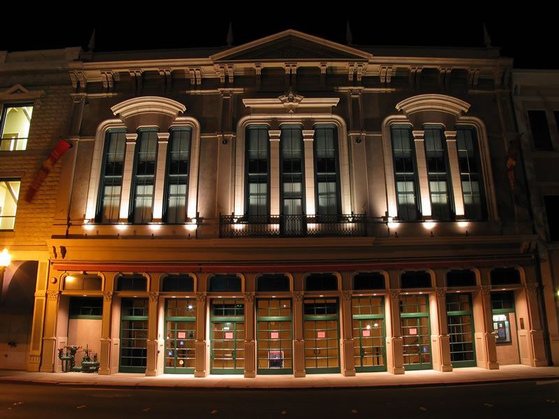 Illuminated historic building facade at night with ornate columns and many lit windows