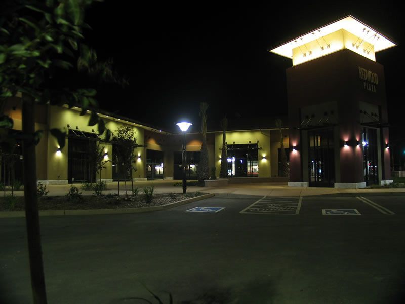 Nighttime view of a lit building entrance and parking lot, with a glowing tower sign
