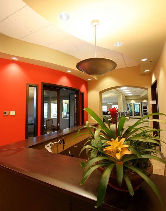 Modern lobby with red walls, glass doors, and a planter on a reception desk